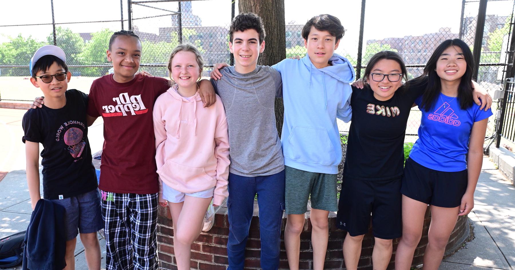 Ethical Culture Fieldston School Middle School Students stand together arms around each other smiling in the field