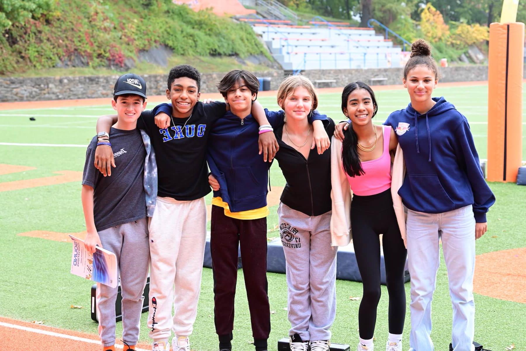 道德文化 Fieldston School Middle School students stand together in arms on athletic field