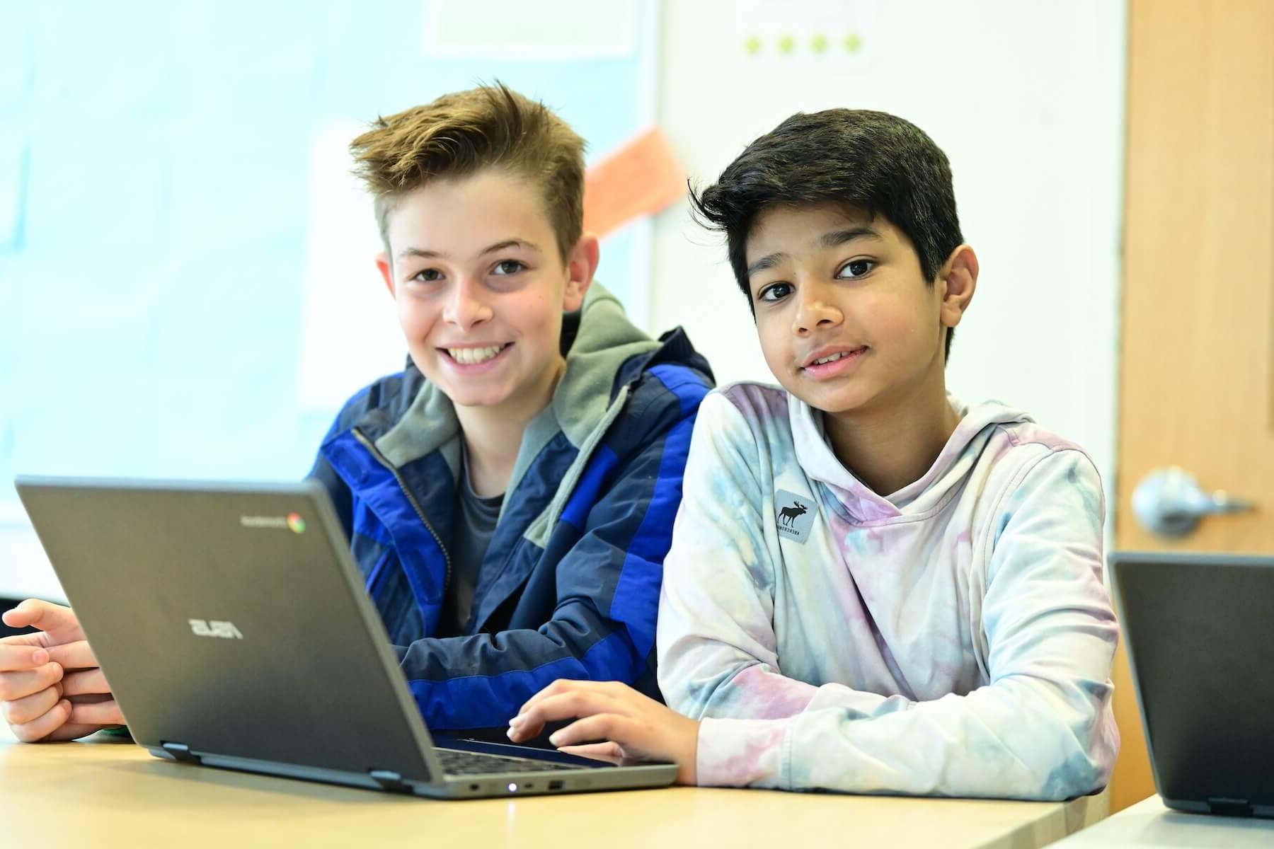 Ethical Culture Fieldston School Middle School students working together on computer pause to smile for the camera