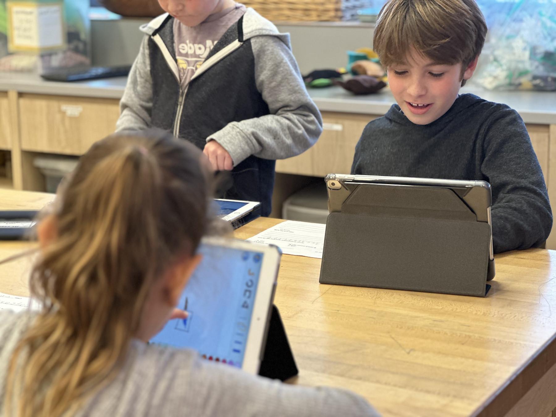 Group of three Fieldston Lower students work together on iPads in classroom.