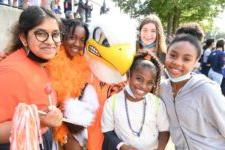 Group of students pose and smile with eagle mascot at homecoming